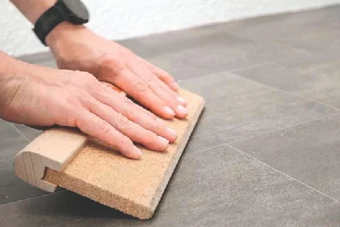 Person verlegt Vinylboden mit Andrückroller